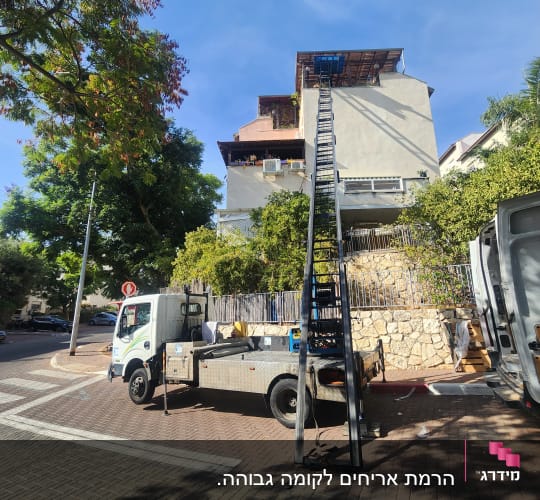 משאית עם מנוף ליד בניין מגורים